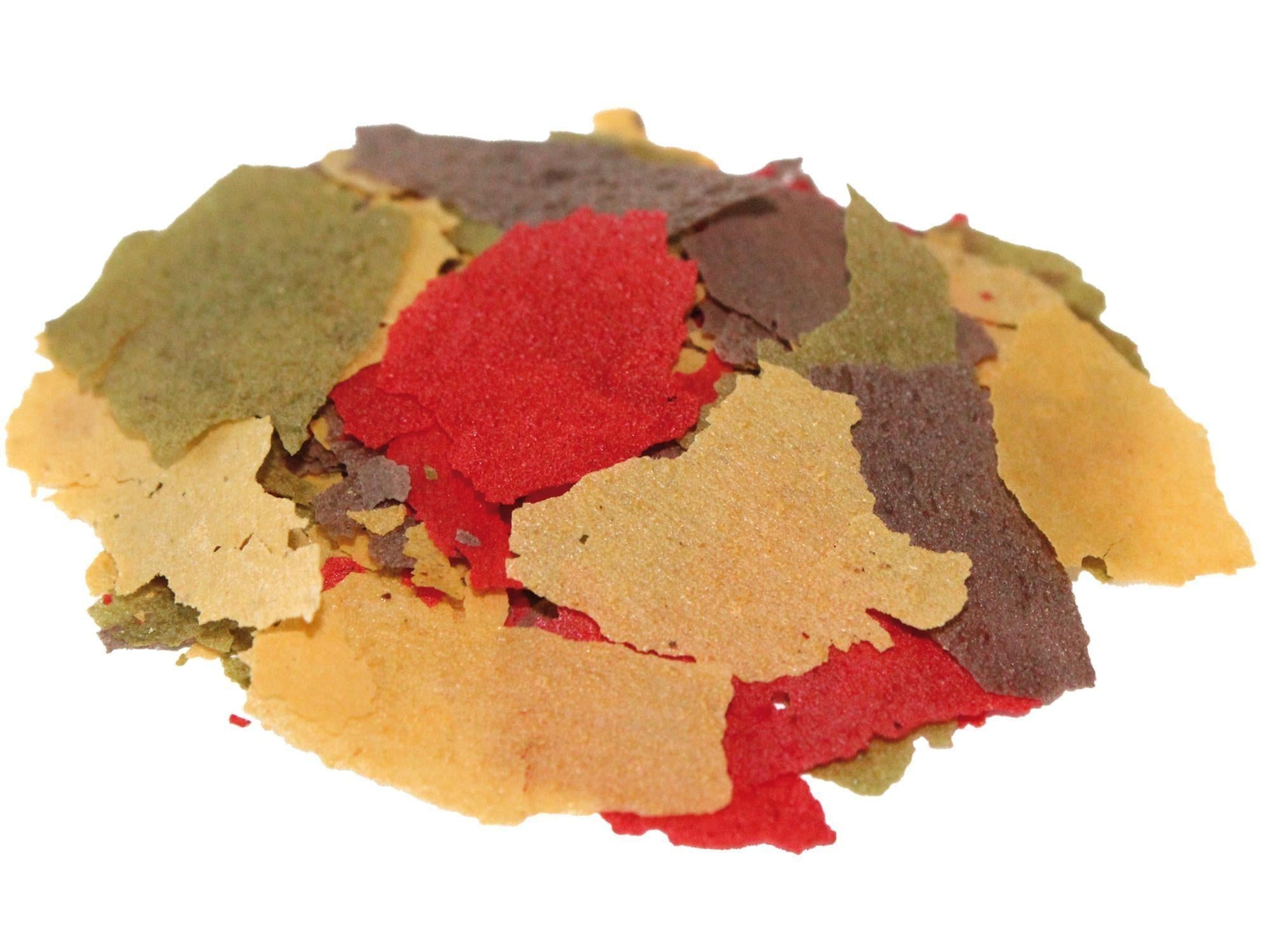 A heap of BioFood Flakes fish food in various colors: red, green, brown, and beige.
