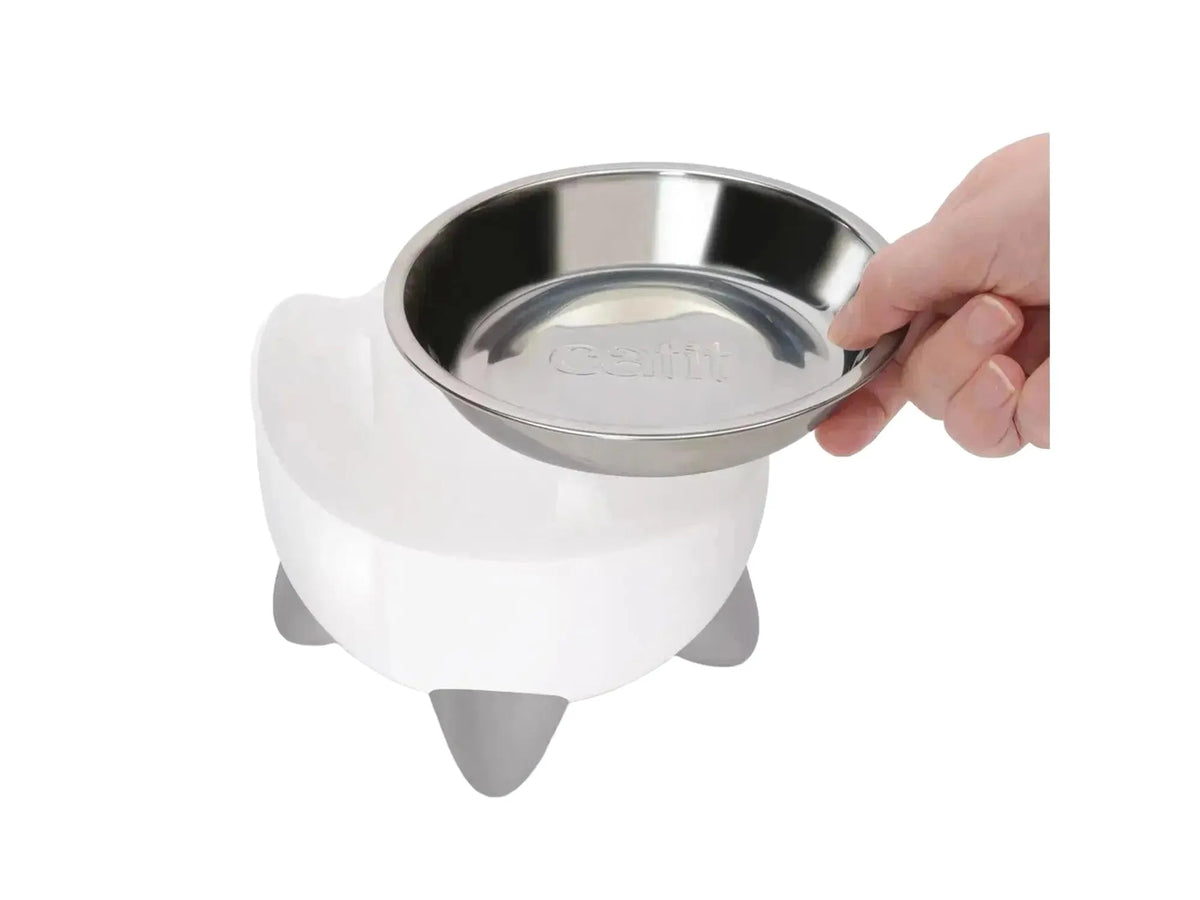 Hvit Catit PIXI vannfontene og matskål sett med avtakbar stålskål, holdes av en hånd.