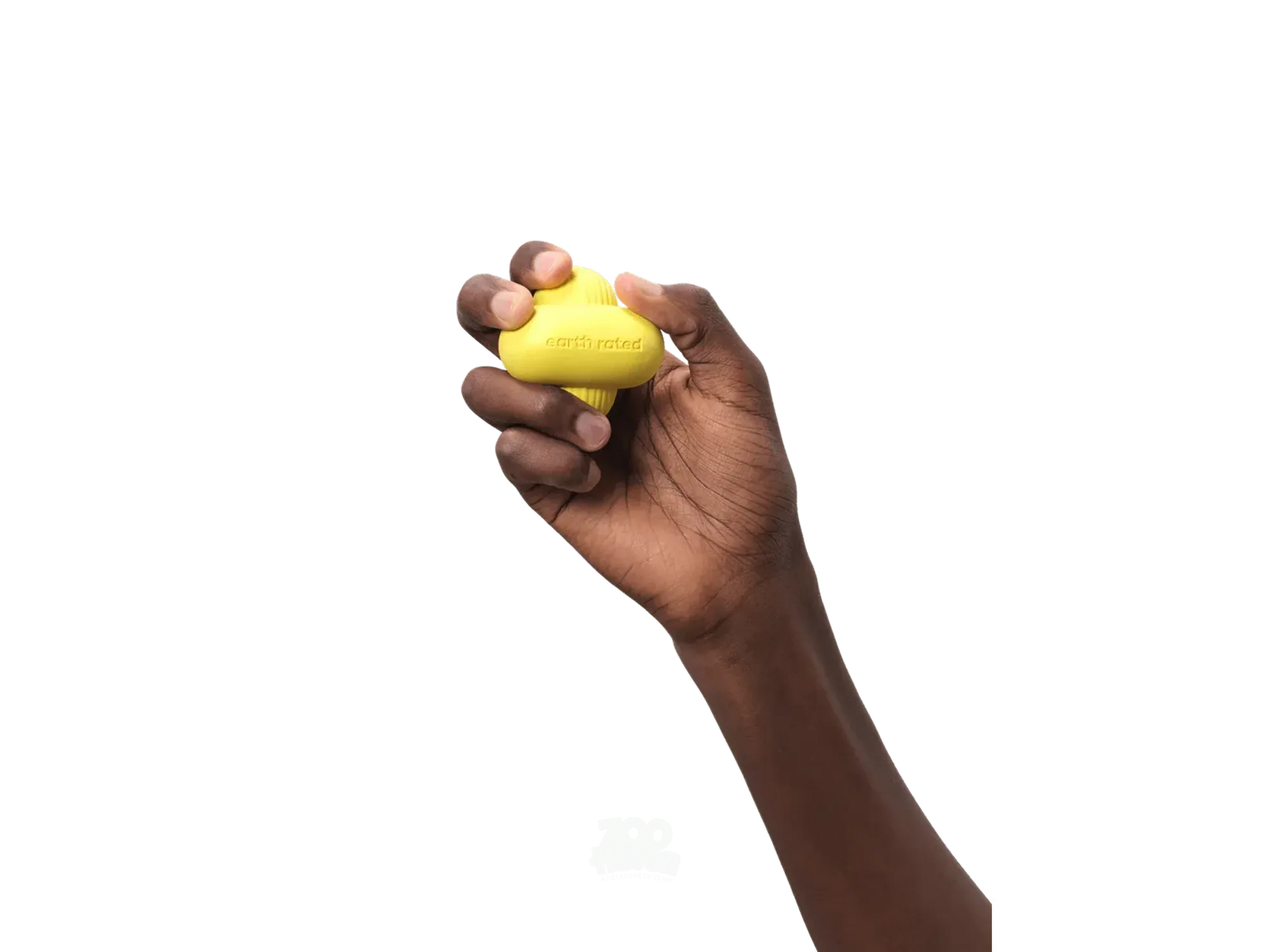 Mørk hånd holder en gul, avlang Earth Rated Fetch Toy i naturgummi med luftkanaler.