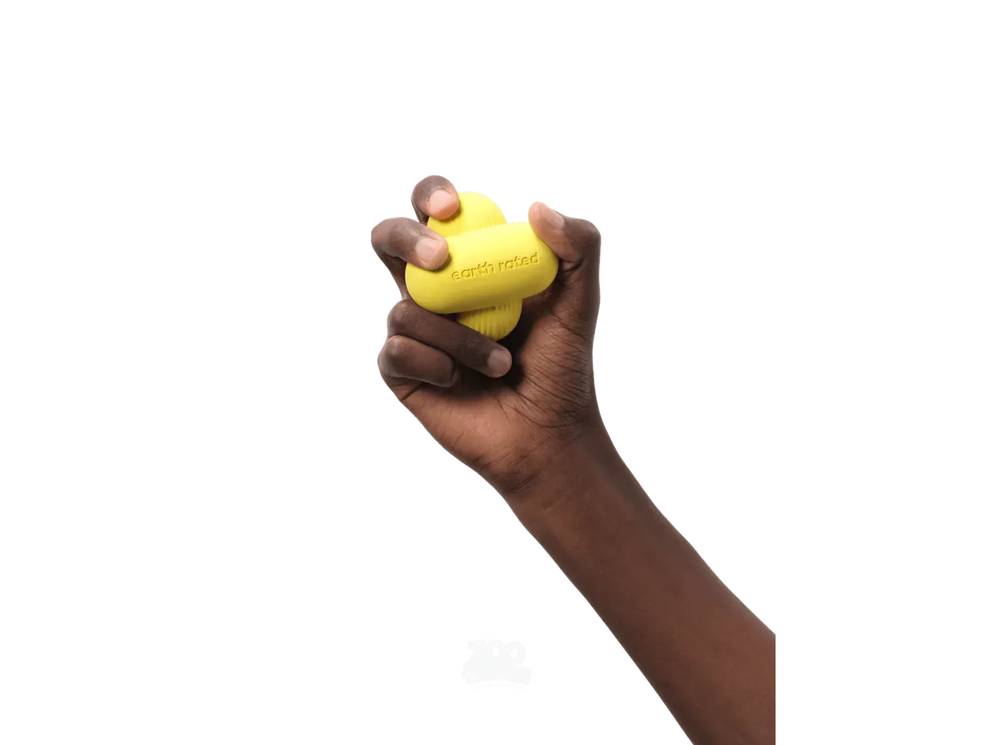 En mørk hånd holder en gul Earth Rated Fetch Toy i naturgummi, med logoen synlig.