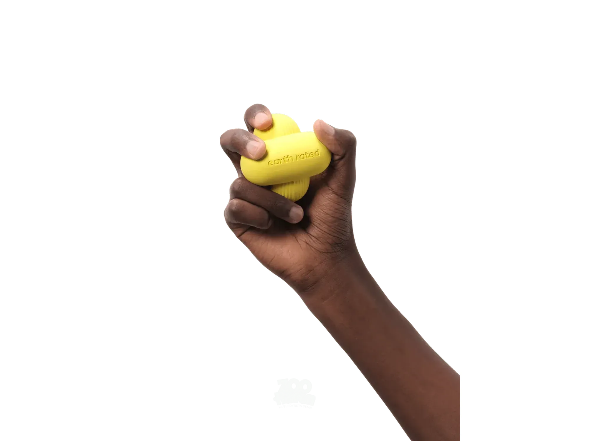 En mørk hånd holder en gul Earth Rated Fetch Toy i naturgummi, med logoen synlig.