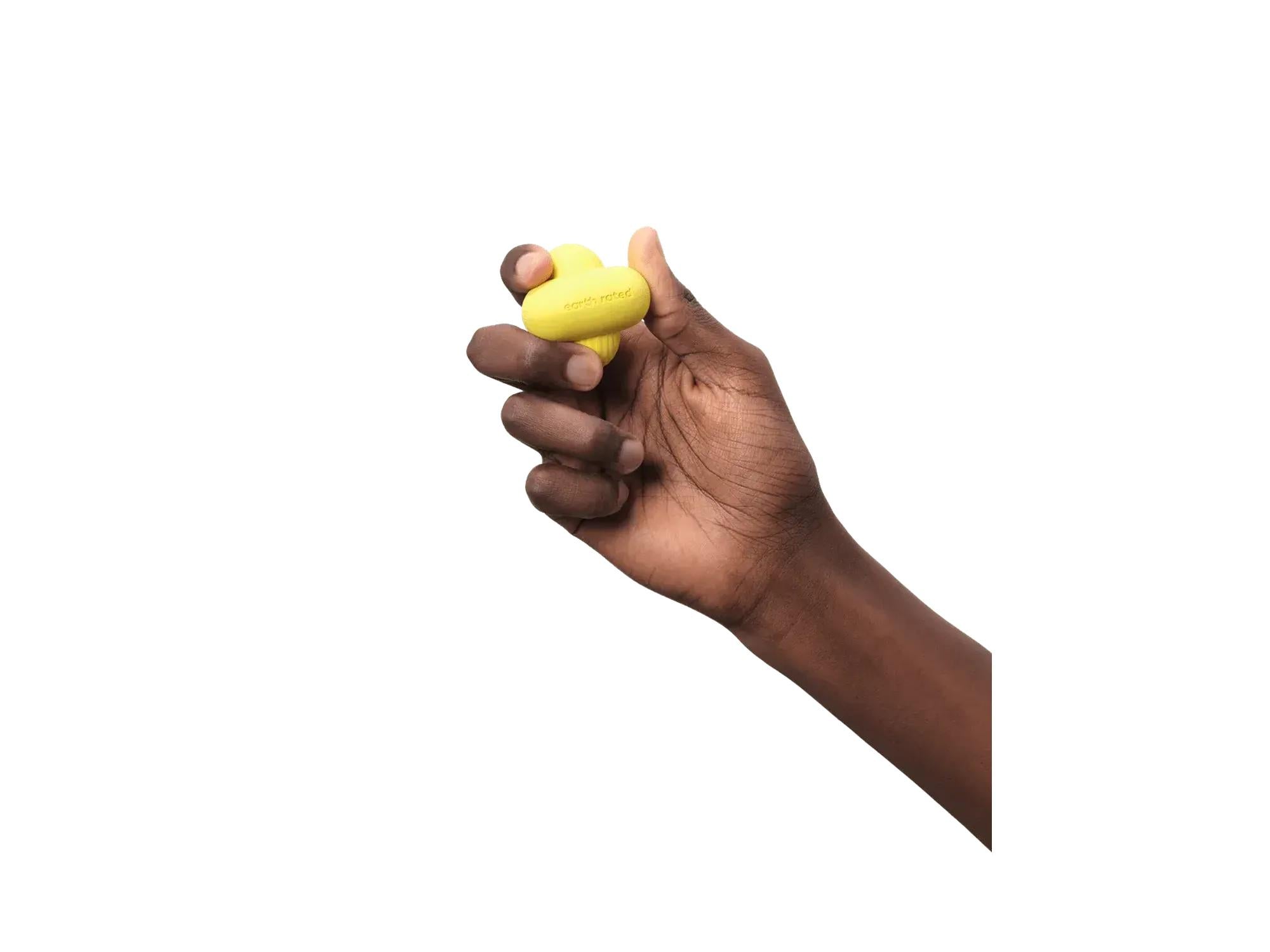 En hånd holder en gul Earth Rated Fetch Toy i naturgummi, med uregelmessig form og logo.