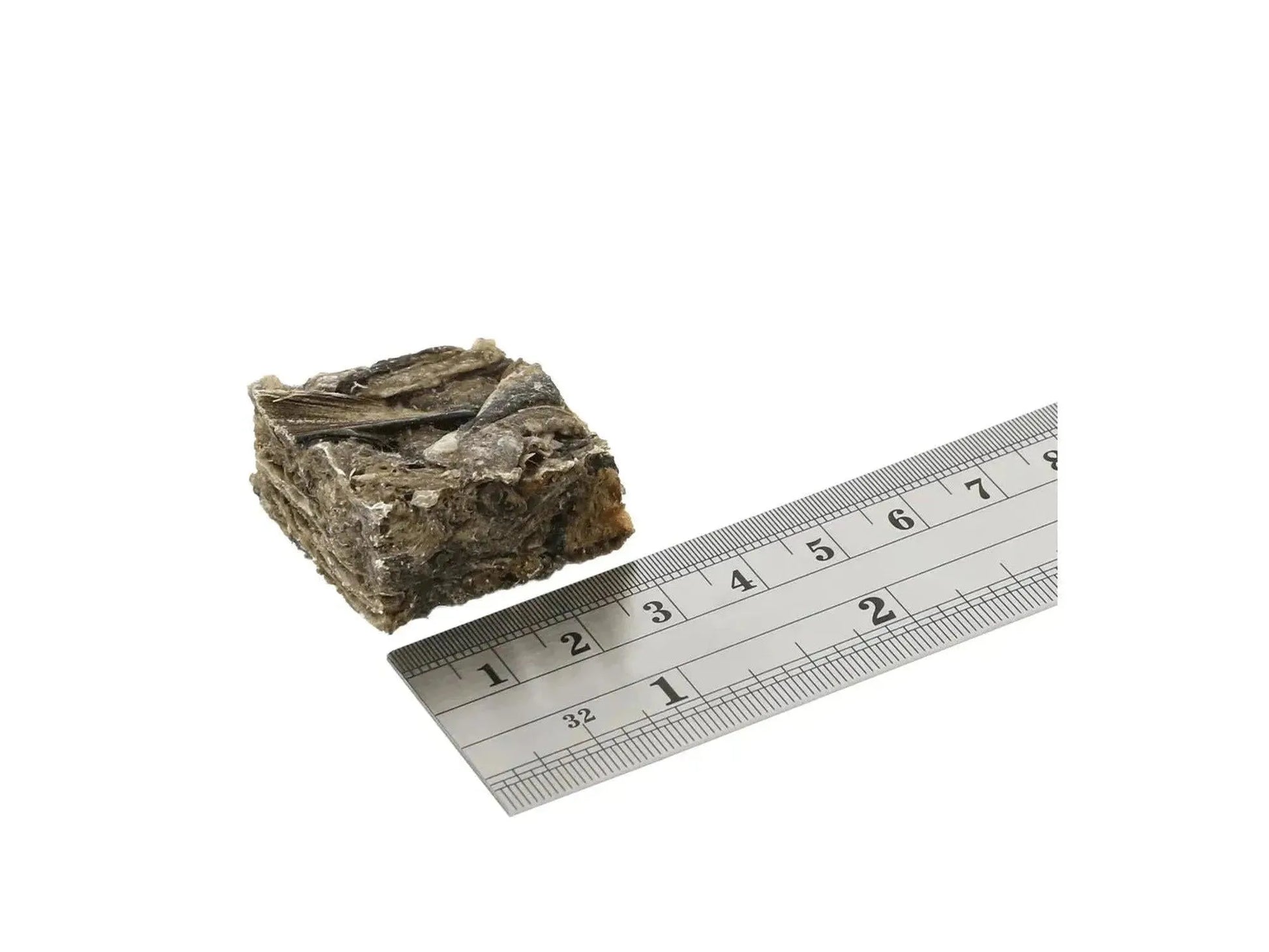 Brun, grov terning av fiskeskinn (ca. 25 mm) ved siden av en linjal for størrelsesreferanse.