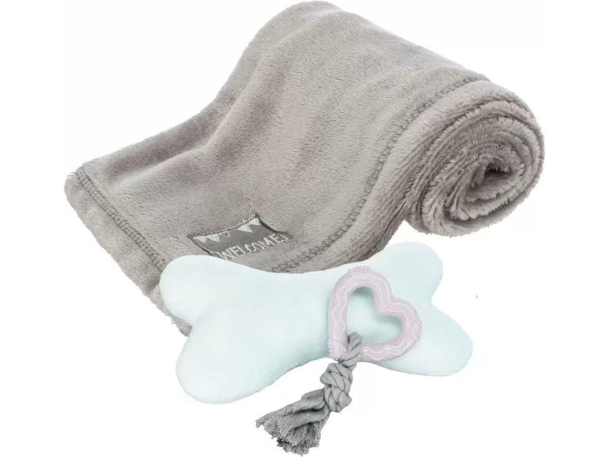Grått fleeceteppe med "WELCOME" tag, lysblå beinplysjleke og grå tyggeleke med rosa hjerte.