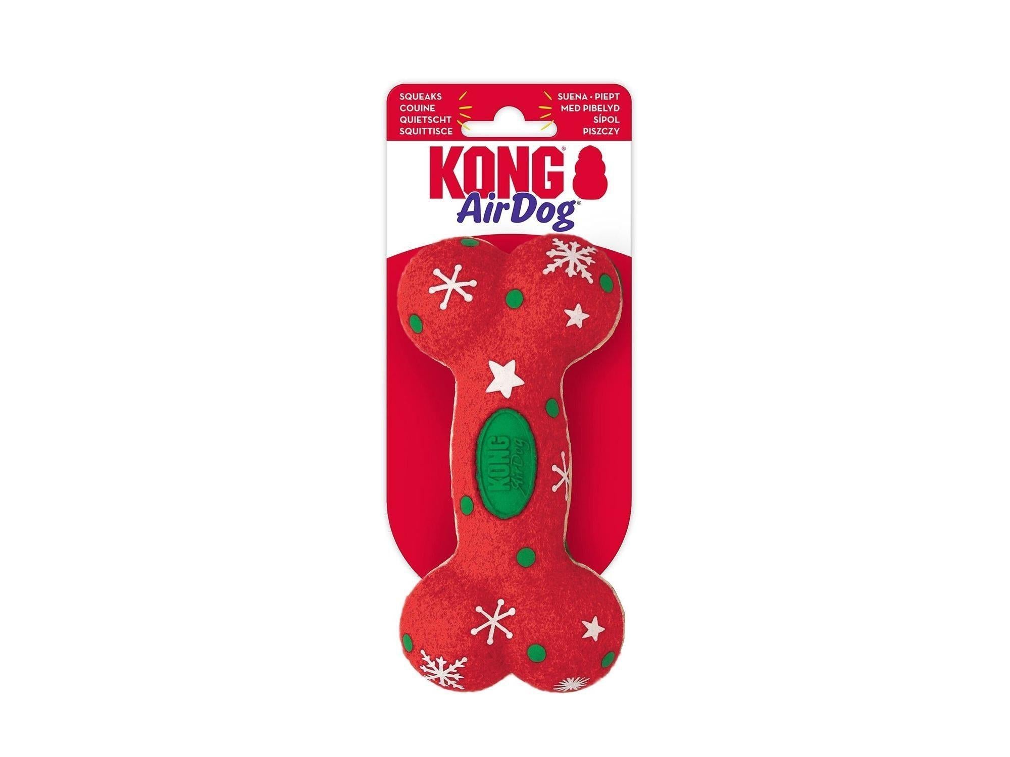 Rød KONG Holiday AirDog Squeaker Bone hundeleke med hvite snøkrystaller og grønne prikker.
