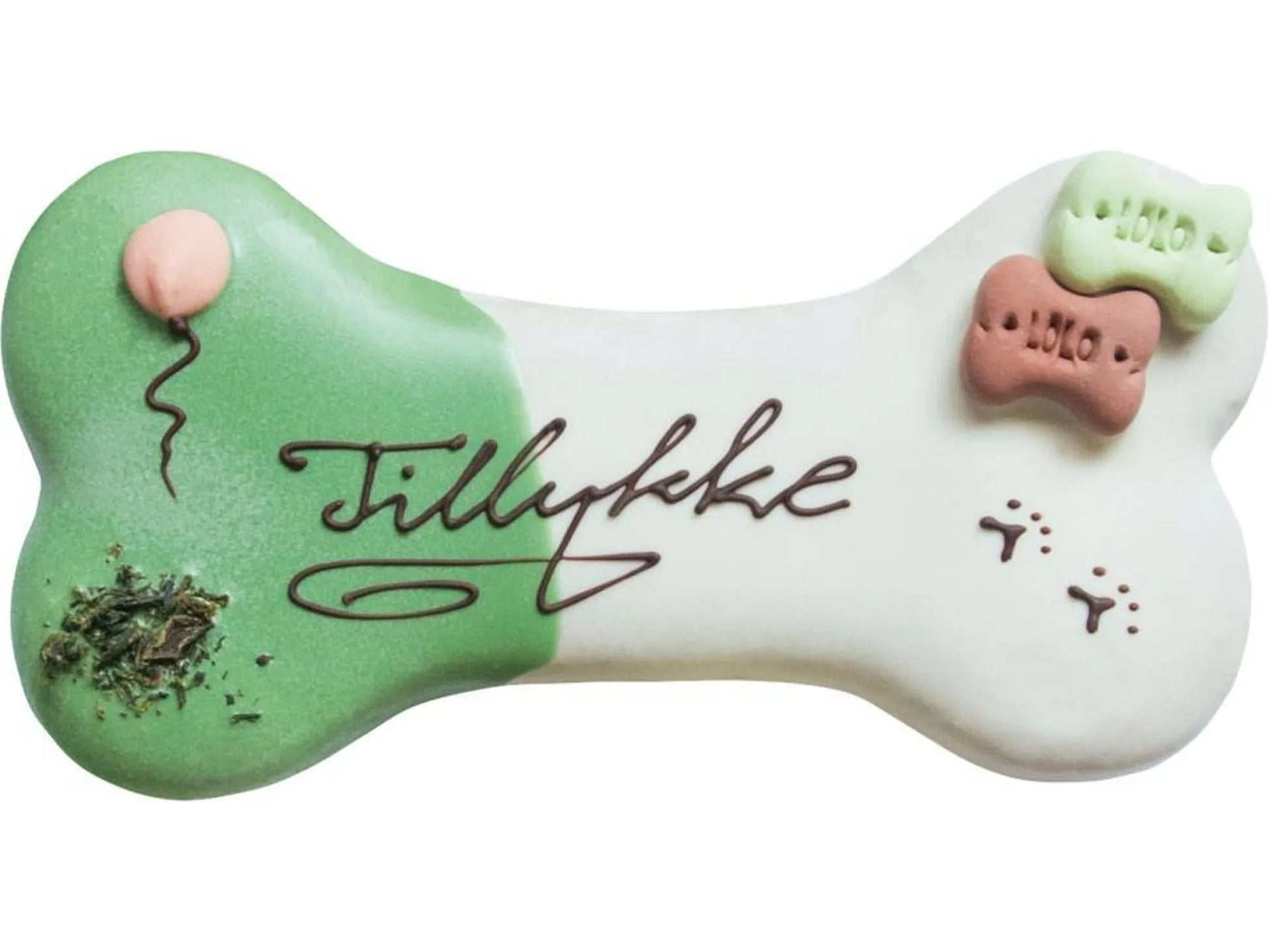 Hundekake formet som et hvitt bein med grønn glasur, "Tillykke" skrevet i sjokolade, ballong, potespor og små godbiter.