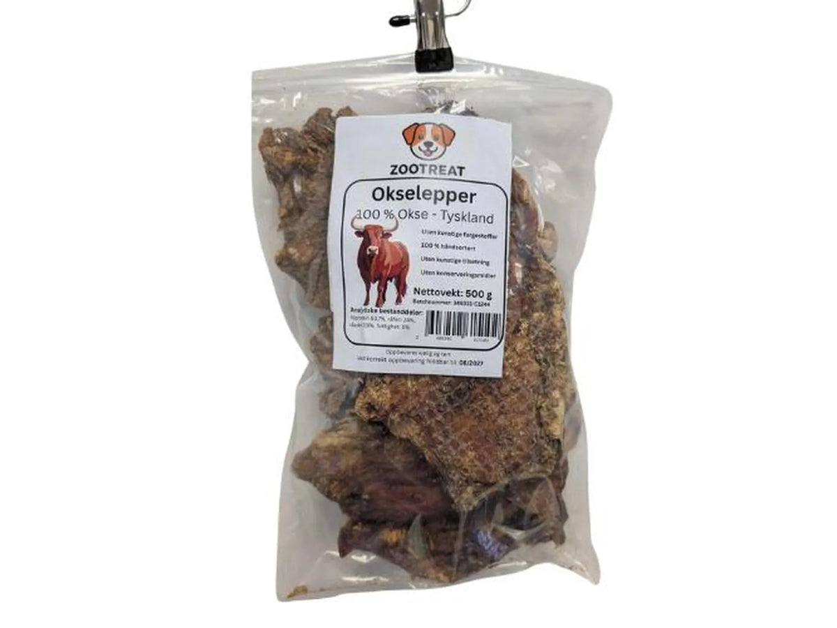 Gjennomsiktig pose med tørkede, mørkebrune okselepper for hund, merket "Zootreat Okselepper 100% Okse - Tyskland, Nettovekt: 500 g".
