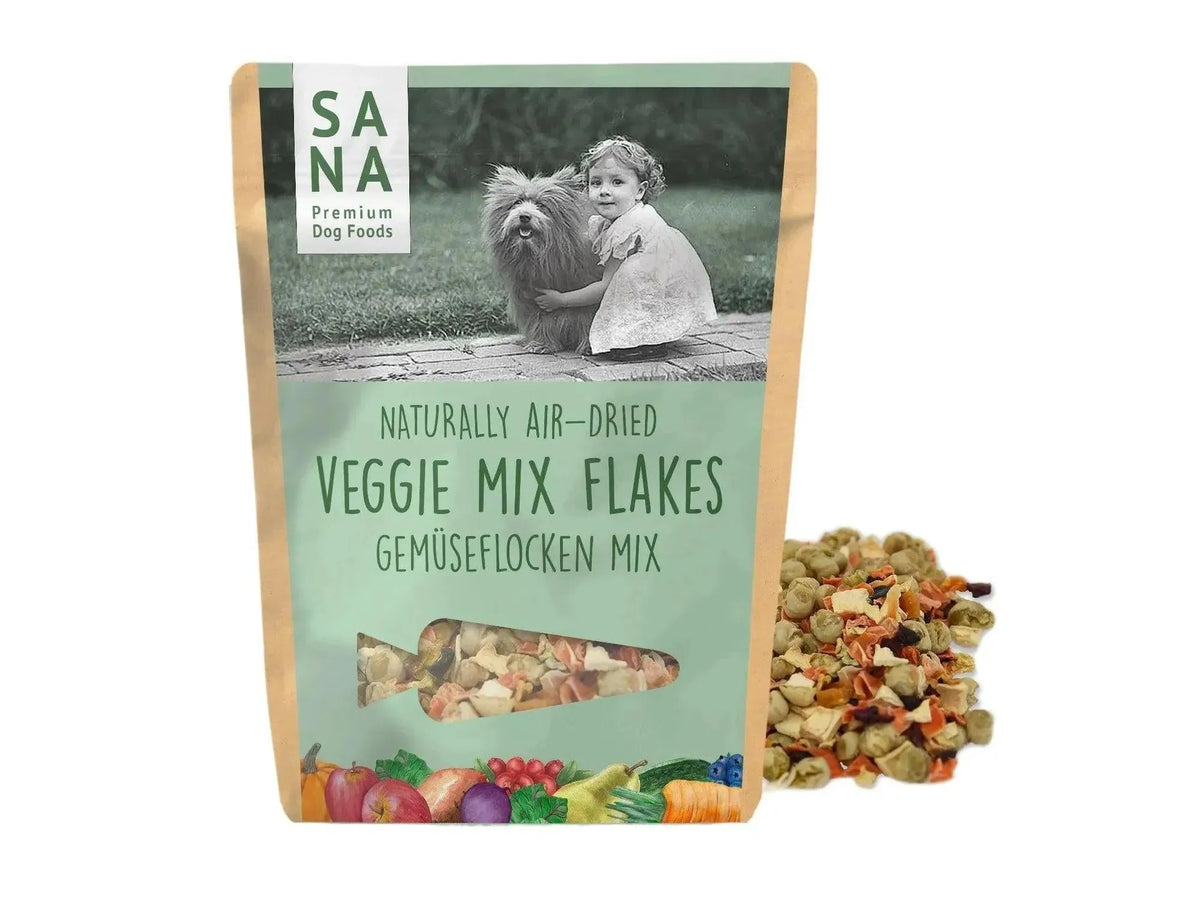 SANA Vegetable-Mix Flakes hundefôr i brun pose med bilde av barn og hund, grønnsaksflak ved siden av.