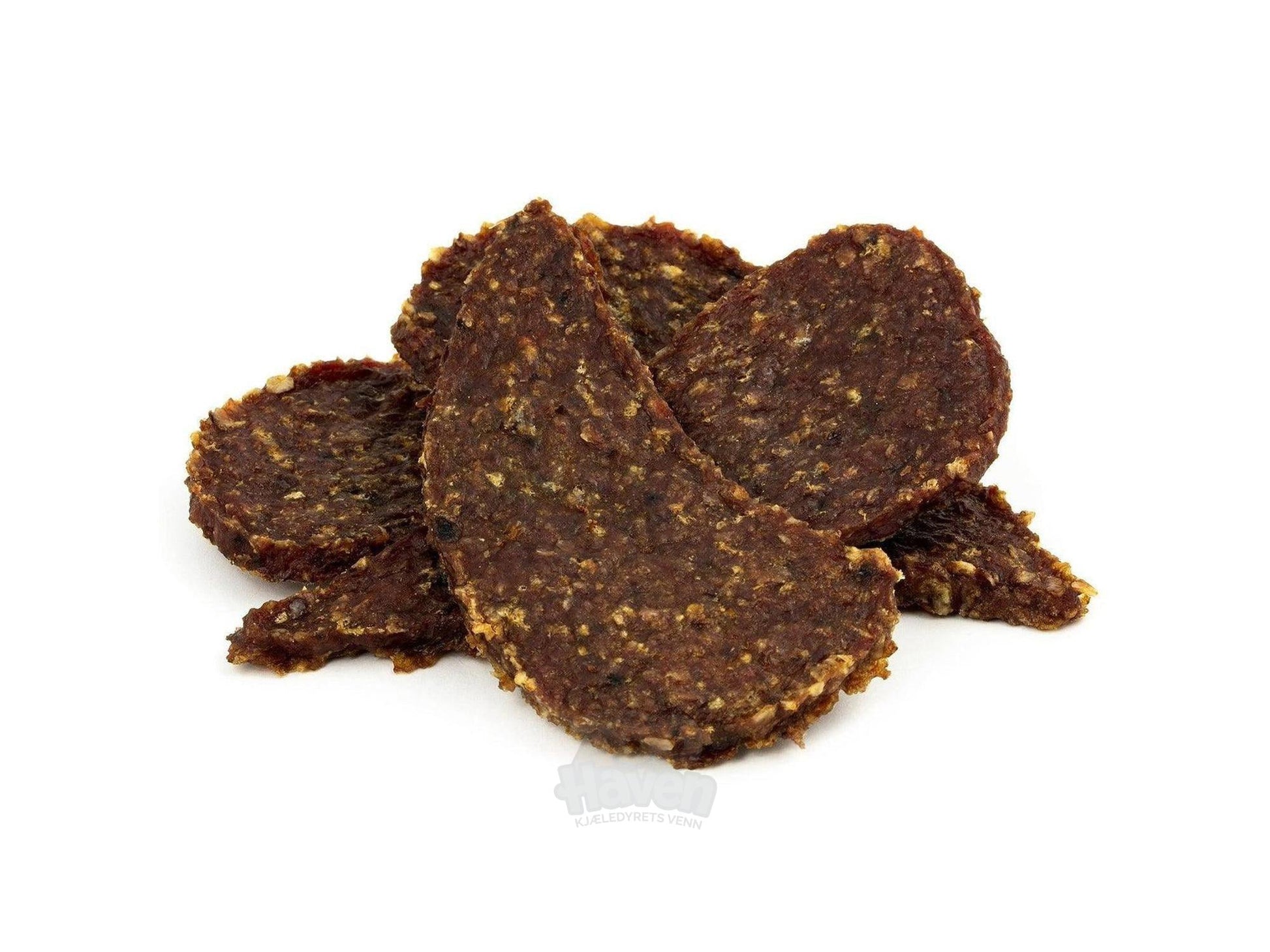 Mørkebrune, ovale andefilet-snacks til hund, med synlige krydderflekker, stablet på hvit bakgrunn.