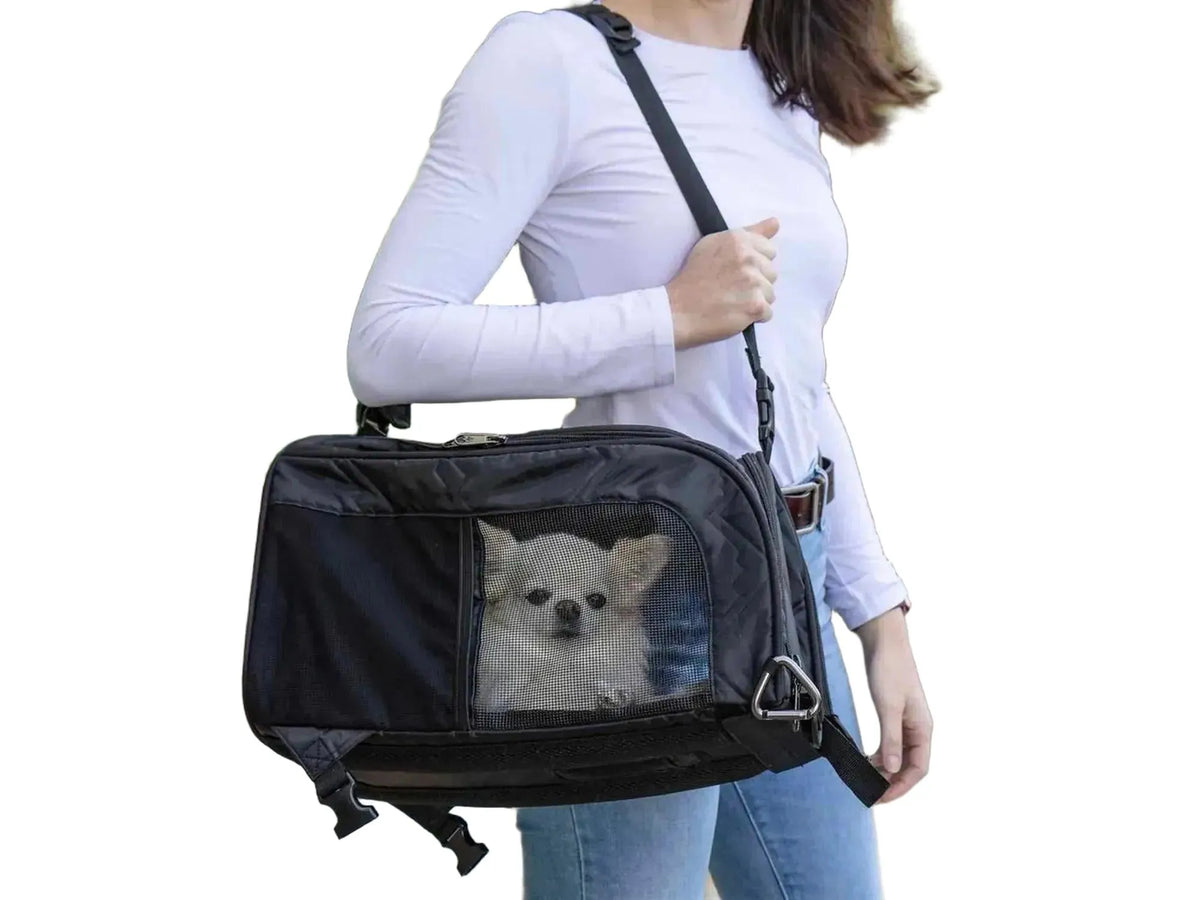 Svart Sherpa Deluxe kjæledyrbærer med nettingvinduer og en liten hvit hund inni, båret over skulderen.
