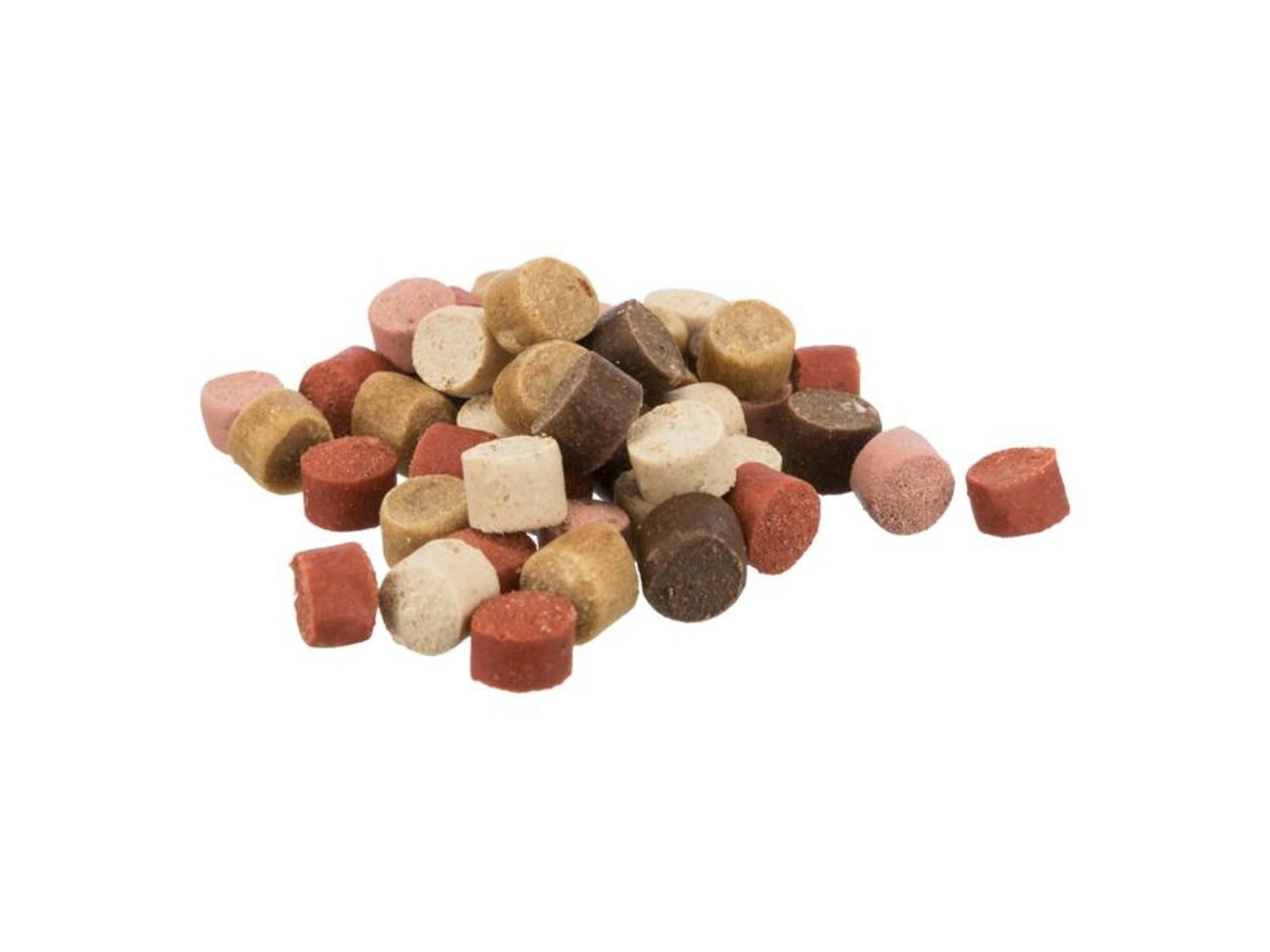 En haug med myke, sylindriske Trainer Snack Mini Dots hundegodbiter i ulike nyanser av brunt, rosa og rødt.