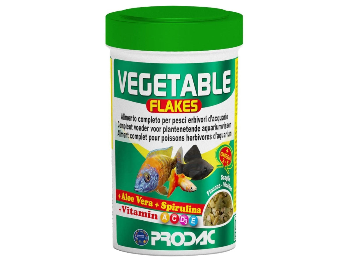 Prodac Vegetable Flakes fiskefôr i hvit beholder med grønt lokk, viser tropiske fisker og flak.
