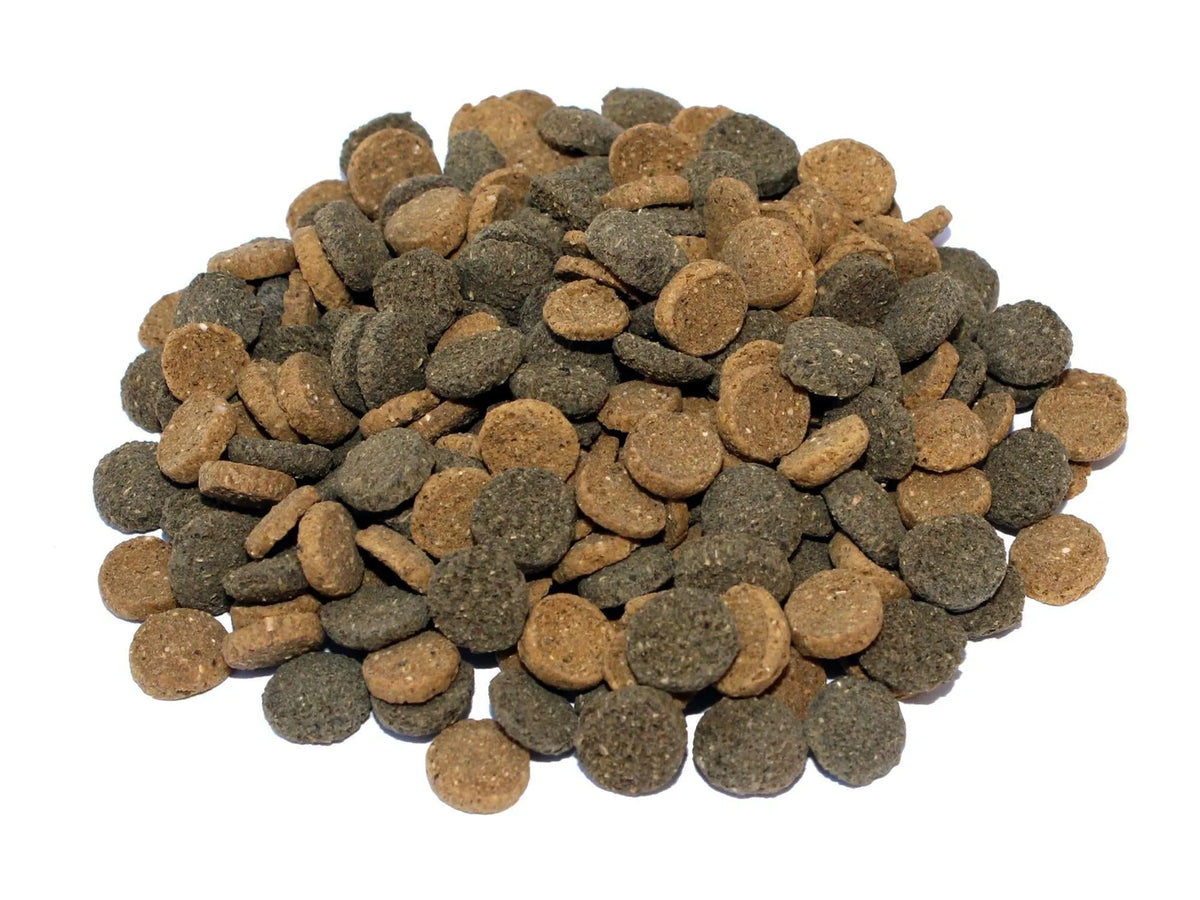 En haug med runde, mørkebrune og gråbrune wafers for akvariefisk og reker.