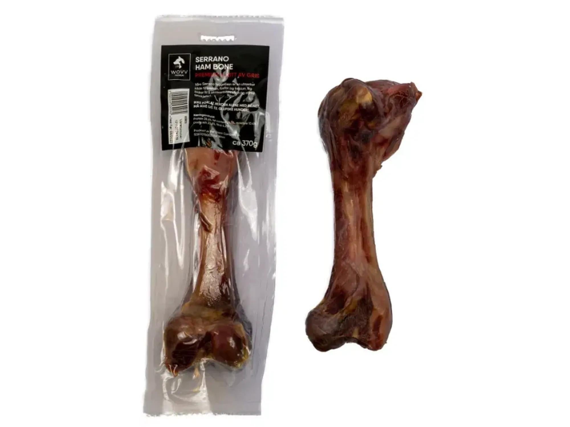 Wovv Serrano Ham Bone, et mørkebrunt halvtørket skinkebein for hund, i og uten emballasje.